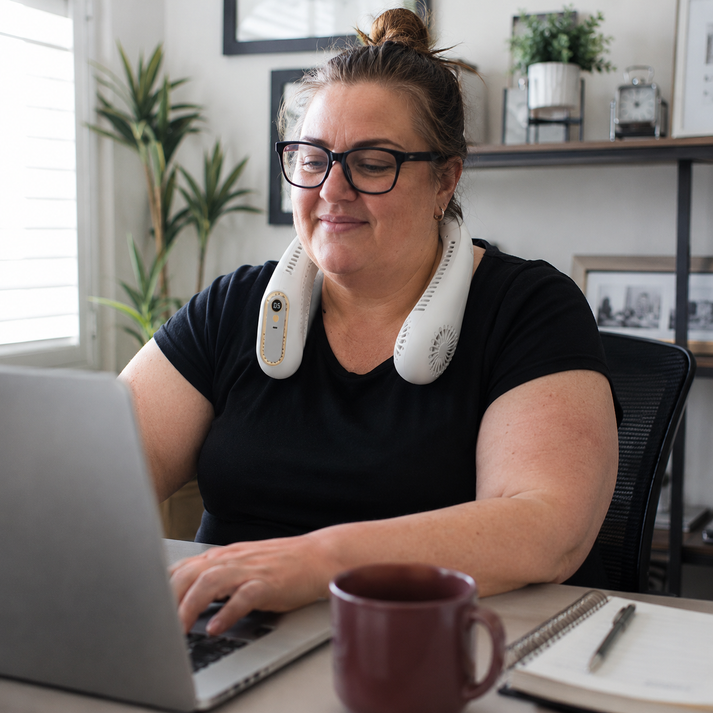 Woman working at desk while wearing a quiet neck fan